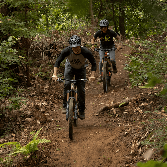 Male and female mountain bike riders wearing TOS classic raglan and Missing Link tee on a trial. 