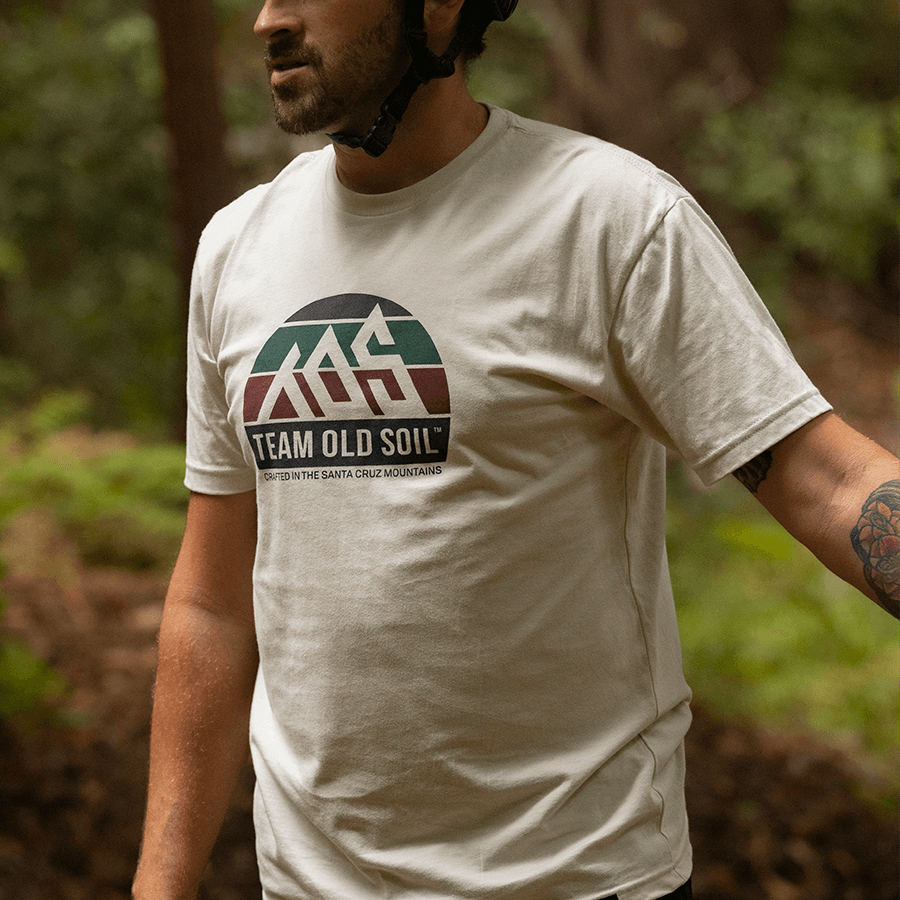 Male wearing cream Rainbow TOS Premium shirt in the forest.