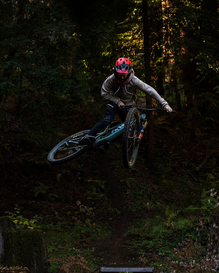boy jumping a santa cruz bike while wearing a Khaki/tan extra soft fleece pullover front in the forest
